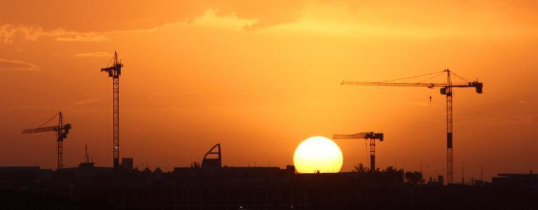Hijskranen tegen de hemel bij schemering.